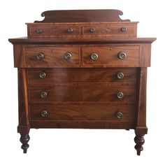 a wooden dresser with many drawers and knobs on the bottom drawer, against a white background