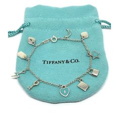 Tiffany & Co Sweet, Feminine Mini Dangle Charm Bracelet. 10 Mini Tiffany & Co Charms, 4 Feature The Popular Tiffany Blue Enamel. Hallmarked "Tiffany & Co / Ag925". 925 = Sterling Silver. 6.50 Inches End To End. 5.2 Grams. Includes Original Tiffany & Co. Pouch And Box Retired Piece. Tiffany & Co Sterling Silver Blue Enamel Mini Charm Bracelet. Condition Is "Pre-Owned". Shipped With Usps First Class. Tiffany And Co Mini Double Heart Tag, Tiffany Bangle Tiffany & Co., Tiffany Charm Bracelet Tiffany & Co., Sterling Silver Bangle Bracelets Tiffany & Co., 1960s Tiffany & Co. Jewelry, Mini Charm, Dangle Charms, Tiffany Blue, Silver Blue