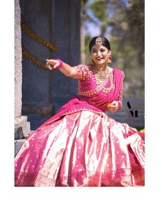 a woman in a pink and gold dress posing for the camera with her arms outstretched