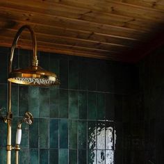 a green tiled bathroom with gold faucet and shower head