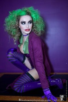 a woman with green hair and purple makeup is posing for a photo in her costume