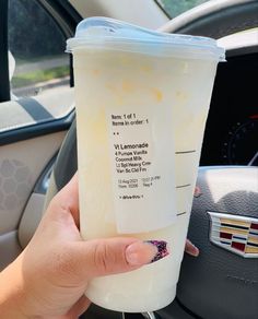 a person holding up a plastic cup in their hand while sitting in the driver's seat