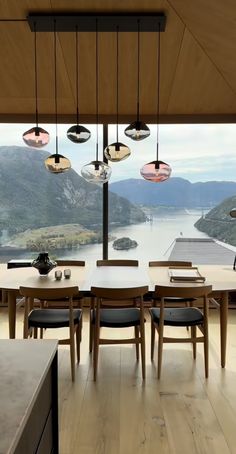 a dining room table and chairs in front of a large window looking out on the water