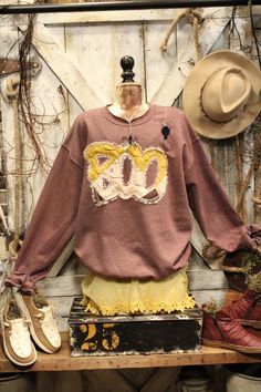 an old fashion clothing on display in front of a wooden wall with shoes and hats