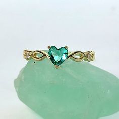 a green heart shaped ring sitting on top of a rock