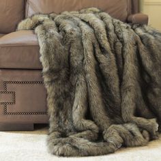 a large furry animal laying on the floor next to a brown leather chair and ottoman