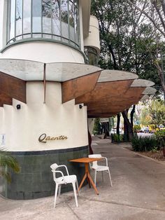 two white chairs sitting next to each other near a building