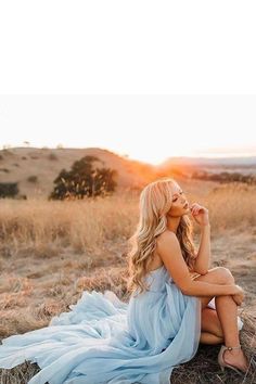 a woman sitting on top of a dry grass field