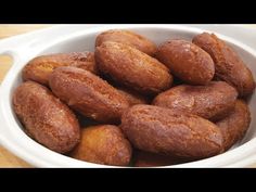 a white bowl filled with doughnuts on top of a wooden table