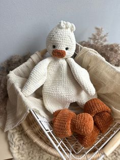 a crocheted teddy bear sitting in a basket on a table next to some blankets