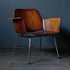 a wooden chair sitting on top of a hard wood floor next to a blue wall