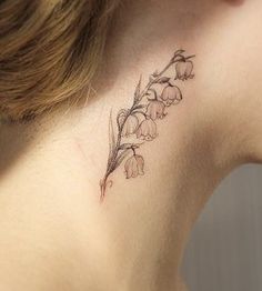 a woman's neck with a flower tattoo on the back of her left ear