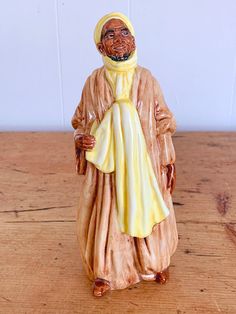 a ceramic figurine of an old man wearing a yellow robe