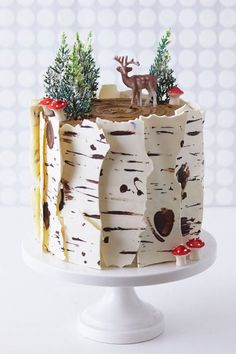 a cake decorated with birch trees and reindeer figurines