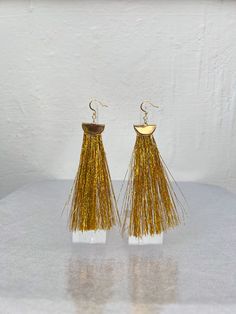 Gift yourself or a friend a unique set of gold metallic tinsel tassel earrings for a special occasion. They feature 18K gold and a gold tinsel fringe that dangle perfectly from your ears for a spectacular look. Fringe is very soft! Materials: 18K gold hook, gold half moon, gold tinsel fringe Fringe Length: 3in Yellow Fringe Jewelry For Party, Gold Tassel Jewelry For Celebration, Gold Jewelry With Tassels For Celebrations, Glamorous Gold Dangle Tassel Earrings, Glamorous Gold Fringe Earrings, Gold Fringe Tassel Dangle Earrings, Yellow Dangle Tassel Earrings For Party, Gold Dangle Tassel Earrings With Fringe, Gold Dangle Tassel Earrings