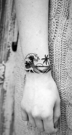 a woman's arm with a tattoo on it that has a wave coming out of the ocean