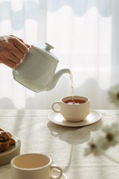 a person pouring tea into a cup on a table