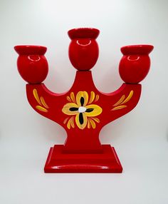 a red vase with three candles in it