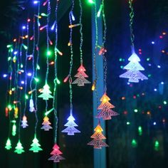 multicolored christmas lights hanging from a pole in front of a tree with snowflakes on it