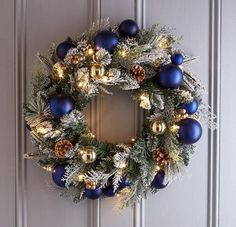 a christmas wreath with blue and gold ornaments hangs on the front door's wall