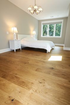 an empty bedroom with wood floors and white bed in the center, two lamps on either side of the bed