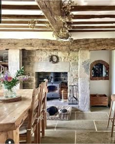 an old stone fireplace in the middle of a living room with wooden chairs and tables