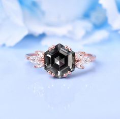 an engagement ring with a black diamond surrounded by white and pink diamonds on a blue background