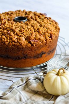 a cake sitting on top of a cooling rack next to a white pumpkin