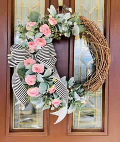 a wreath with pink flowers and greenery on the front door