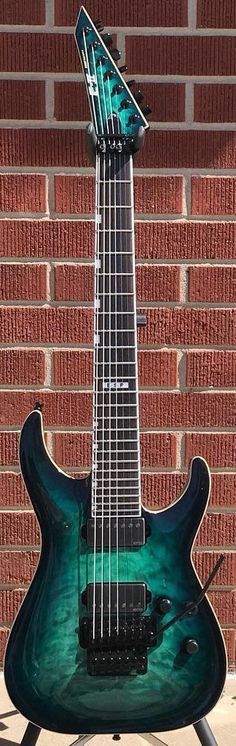 a green guitar sitting on top of a metal stand next to a brick wall in front of a building