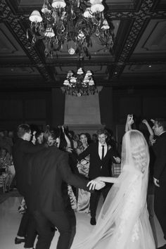 the bride and groom are dancing together at their wedding reception in an ornate room with chandeliers