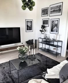 a living room with pictures on the wall and a black coffee table in front of it