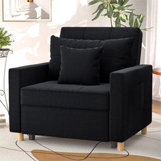 a living room with a black chair and potted plant