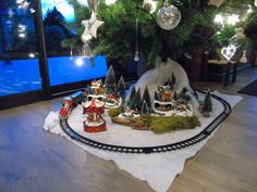 a train track with christmas decorations and trees on it in front of a window at night