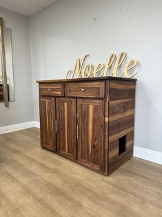 a large wooden cabinet with the word noelfe on it's top in front of a mirror