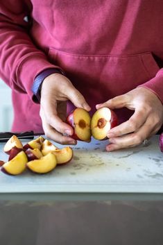 a woman peeling an apple on top of a cutting board next to other fruit pieces