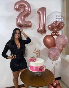 a woman standing next to a cake and balloons