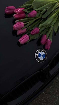 pink tulips are laying on the hood of a bmw car