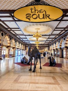 two horses are standing in the middle of a large room with chandeliers and rugs