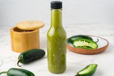 a green bottle filled with pickles next to some other vegetables on a counter top