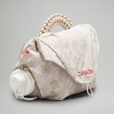 a white purse with a red canada logo on the front and side, is shown against a gray background