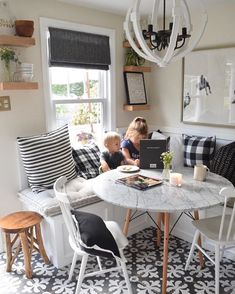 two children sitting at a table in front of a laptop on a rug with black and white patterns