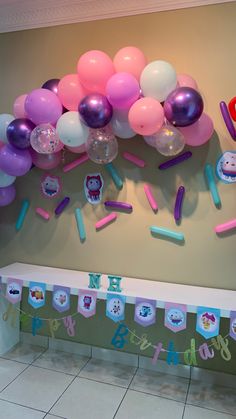 balloons and streamers are hanging on the wall in front of a birthday party banner