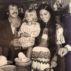 an old black and white photo of three people standing next to a table with cake on it