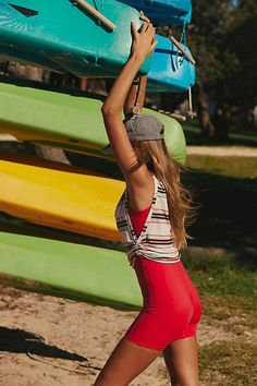 a woman in a red swimsuit holding up a surfboard