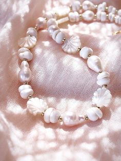 Flanked with luminescent natural white baroque pearls, puka shells, and carved mother of pearl, this unique luxurious pearl choker necklace evokes visions of Hawaii's white sands and soothing shores. Layer this with other shimmering beauties and you'll be ready for your tropical escape. ✦ DETAILS ✦✧ Name: Keao (keh-AH-oh) - The light of the day.✧ Adjustable Necklace.✧ White Puka Shells.✧ Genuine Baroque Freshwater Pearls.✧ Carved Mother of Pearl Seashells.✧ 14kt Gold Filled with lobster clasp.✧ White Shell-shaped Pearl Drop Necklace, White Shell-shaped Jewelry With Pearl Pendant, White Mother Of Pearl Shell Necklace With Pearl Pendant, White Single Strand Pearl Choker, White Mother Of Pearl Necklace For Gift, White Mother Of Pearl Necklace Gift, Gift White Mother Of Pearl Necklace, Spiritual White Mother Of Pearl Jewelry, White Shell-shaped Pearl Pendant Jewelry