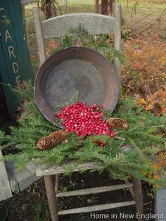 an old chair is decorated with pine cones and berries