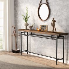 a console table with an oval mirror on the wall above it and some plants in vases next to it