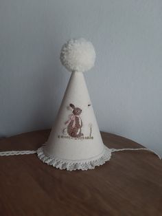 a white hat with a bunny on it sitting on top of a wooden table next to a wall