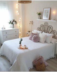 a bedroom with white bedding and lights on the wall